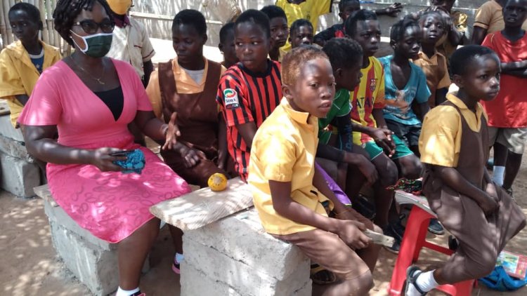 Gyeankontabuo Pupils sit on blocks to learn under a dilapidated structure